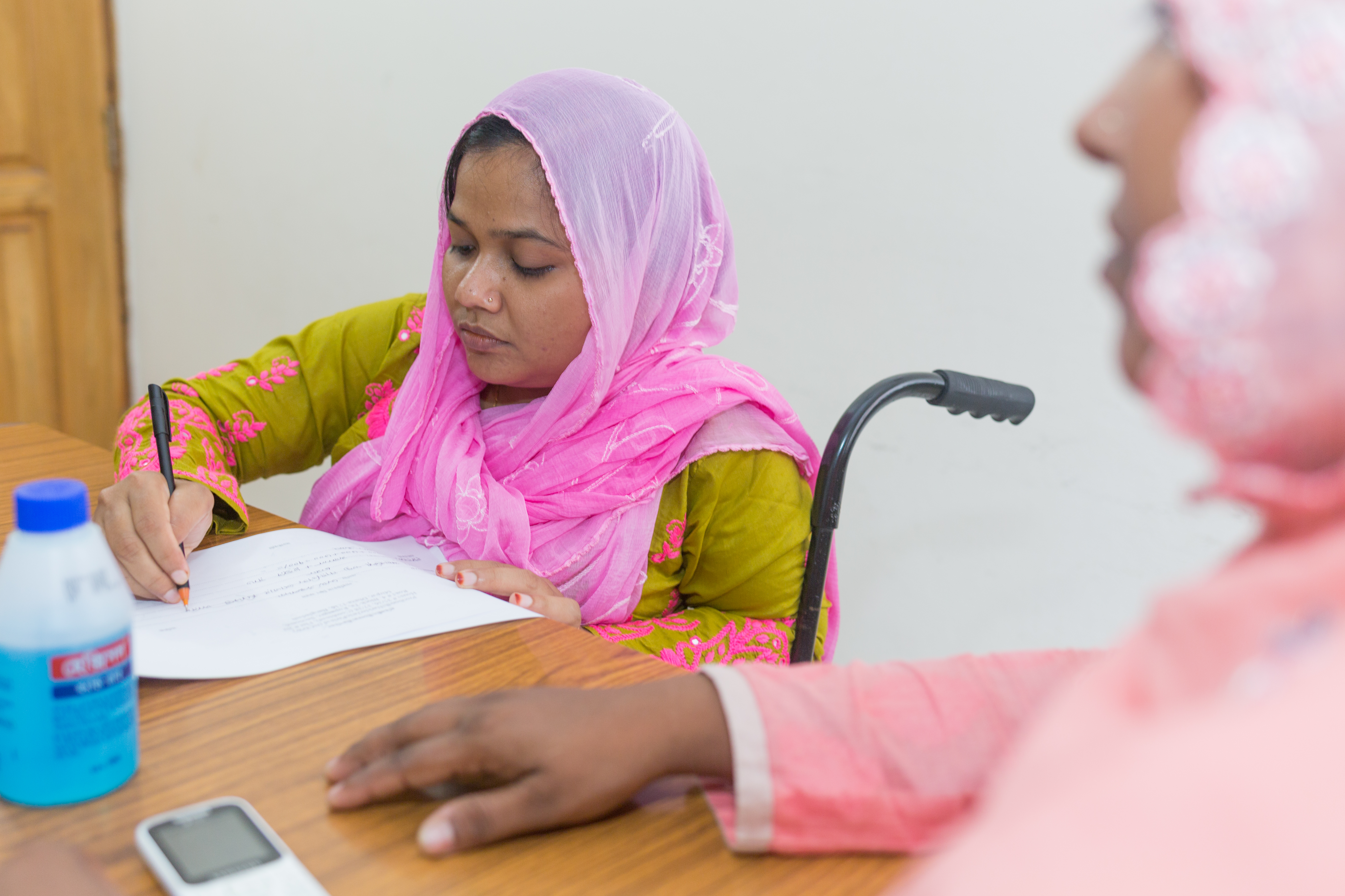 Person in a wheelchair writing on a table